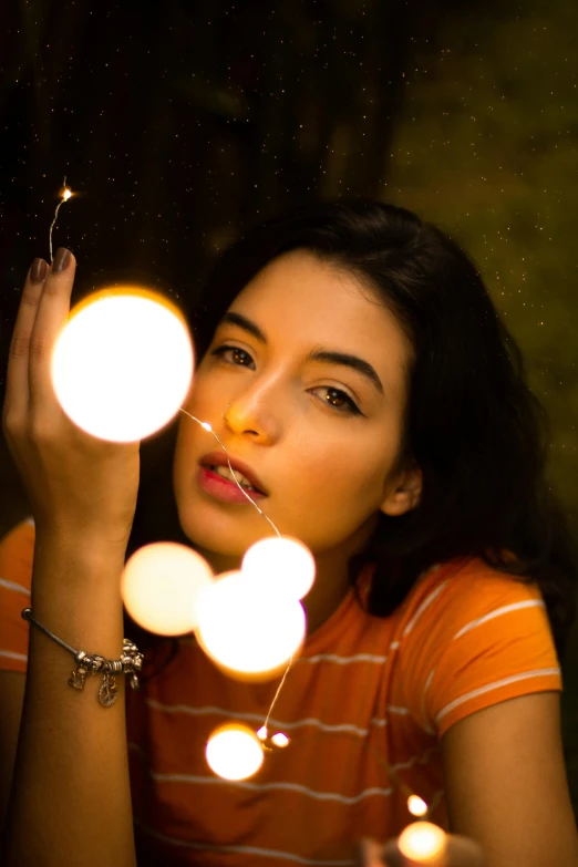 a woman holding a string of lights in front of her face, inspired by Elsa Bleda, pexels contest winner, hanging out with orbs, female camila mendes, 5 0 0 px models, color photograph portrait 4k