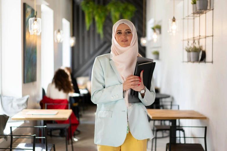 a woman standing in a restaurant holding a tablet, an album cover, inspired by Maryam Hashemi, trending on pexels, hurufiyya, academic clothing, pastel', formal attire, ready for a meeting