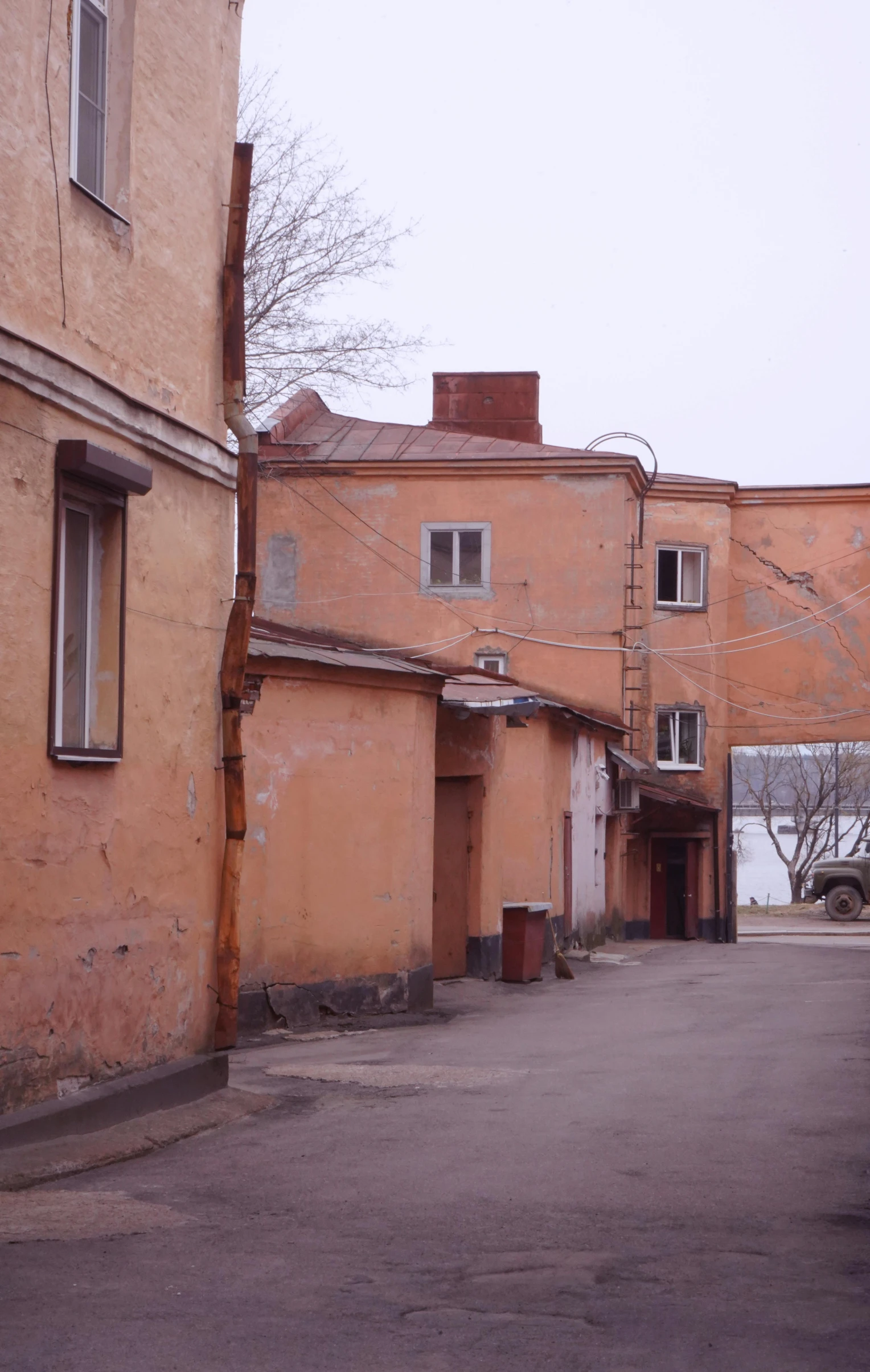 a red fire hydrant sitting on the side of a road, socialist realism, soviet apartment buildings, light - brown wall, orange roof, low quality photograph