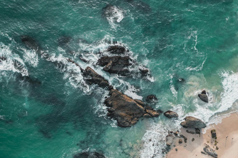 a large body of water next to a sandy beach, pexels contest winner, helicopter view, jagged rocks, teal aesthetic, a green