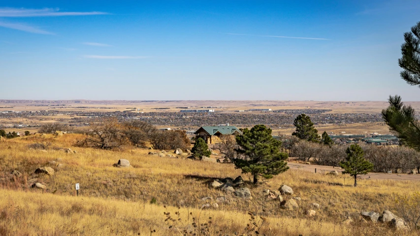 a view of a small town from the top of a hill, by Arnie Swekel, golden grasslands, rustic stone cabin in horizon, amanda lilleston, outdoor photo