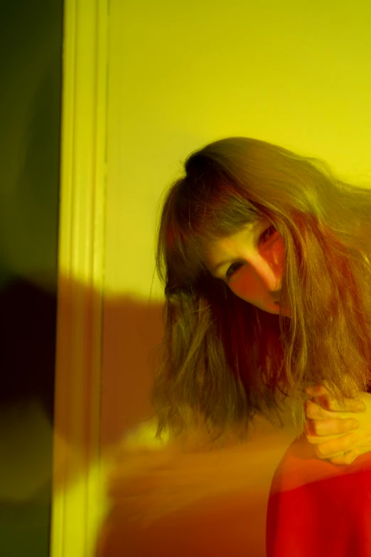 a woman with long hair leaning over a table, inspired by Nan Goldin, kitsch movement, yellow and red, full bangs, high quality photo, psychedelic lighting