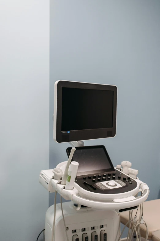 a computer sitting on top of a table in a room, medical equipment, grey, blue