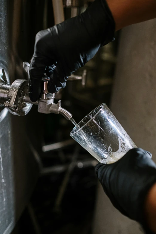 a person pouring a beer into a glass, by Jason Felix, unsplash, process art, biroremediation plant, grey, stainless steel, piping