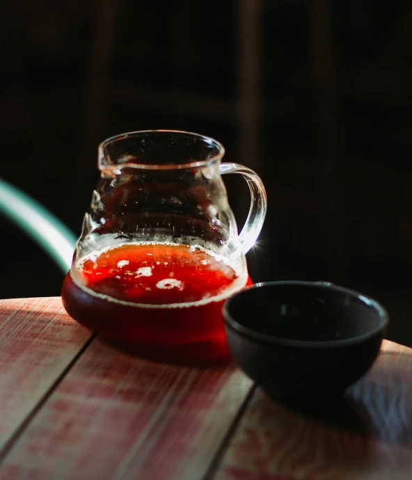 a glass pitcher sitting on top of a wooden table, by Nick Fudge, pexels, red liquid, larapi, glazed, small
