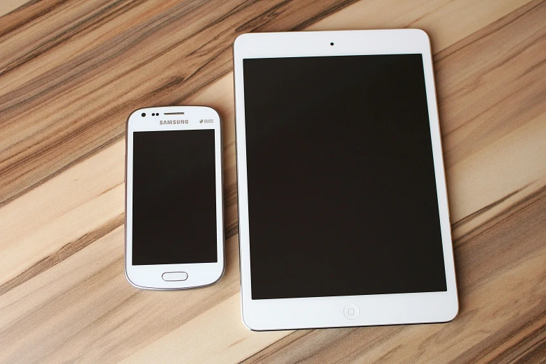 a couple of cell phones sitting on top of a wooden table, by Carey Morris, pexels, ipad pro, square, sleek white, samsung smartthings