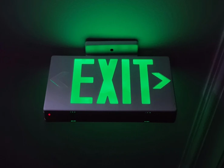 a green exit sign mounted to the side of a wall, pexels, lit from above, jets, next gen, handheld