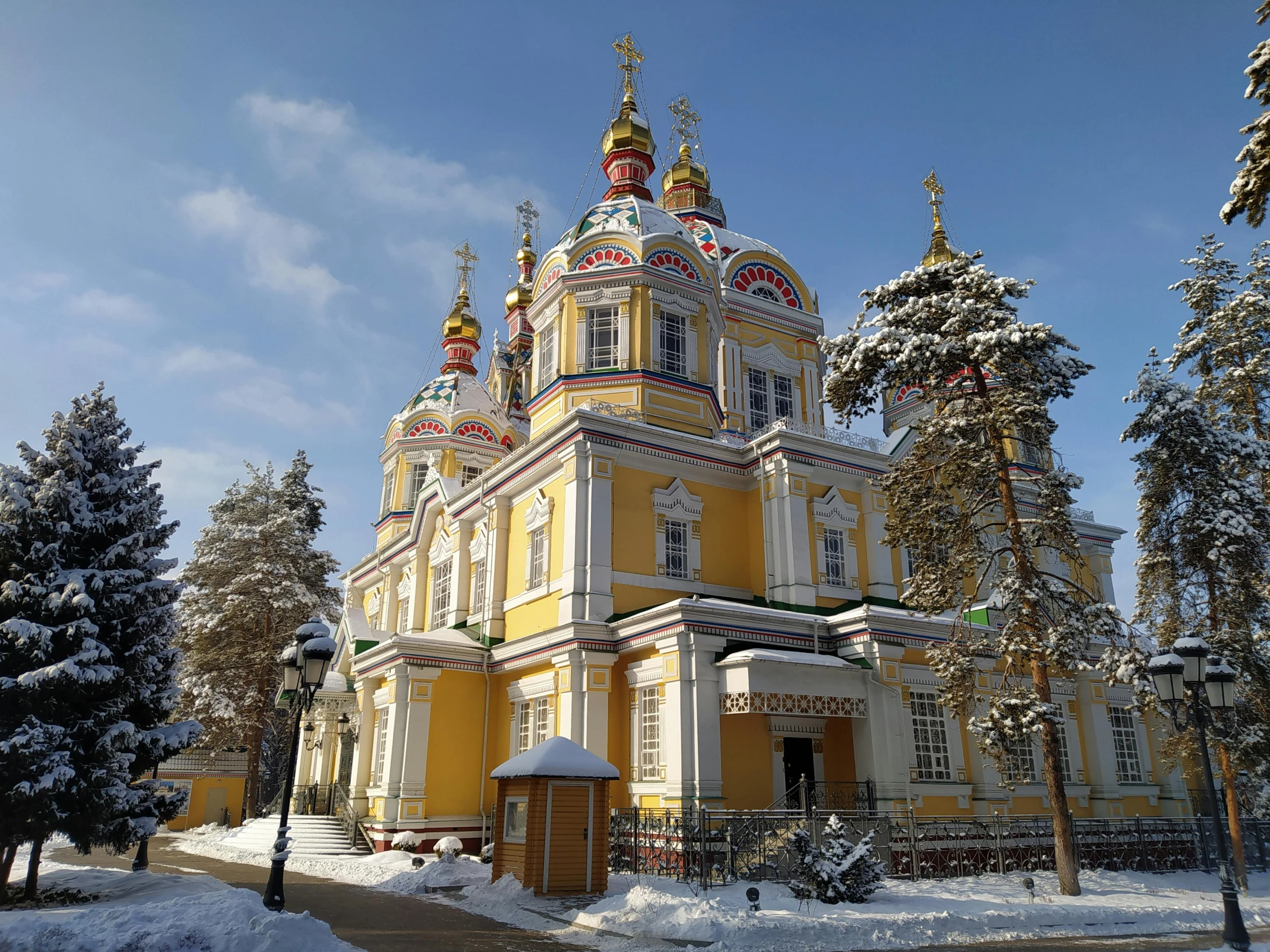 a large yellow building surrounded by snow covered trees, inspired by Illarion Pryanishnikov, art nouveau, church cathedral, red - yellow - blue building, family photo, lead - covered spire