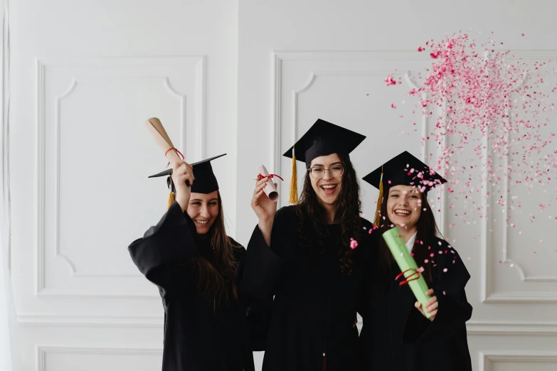 a group of three women standing next to each other, pexels contest winner, academic art, confetti, wearing an academic gown, black, trending on attestation