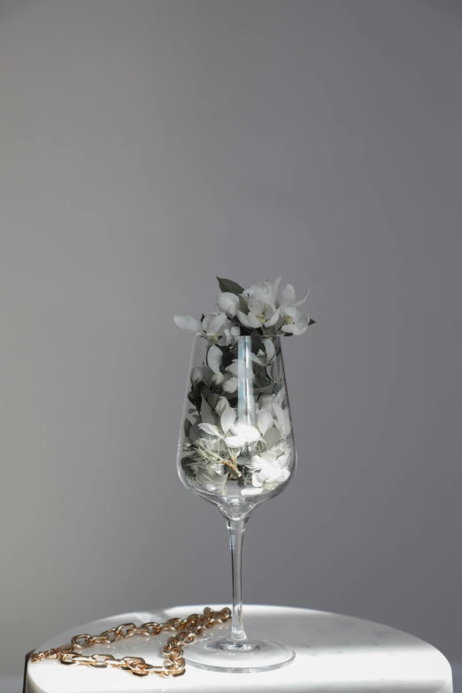 a wine glass sitting on top of a table, inspired by François Boquet, white blossoms, light lighting side view, extra detail, tall