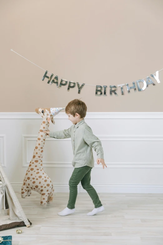a little boy that is playing with a giraffe, by Nicolette Macnamara, happy birthday candles, grey and silver, banner, full product shot