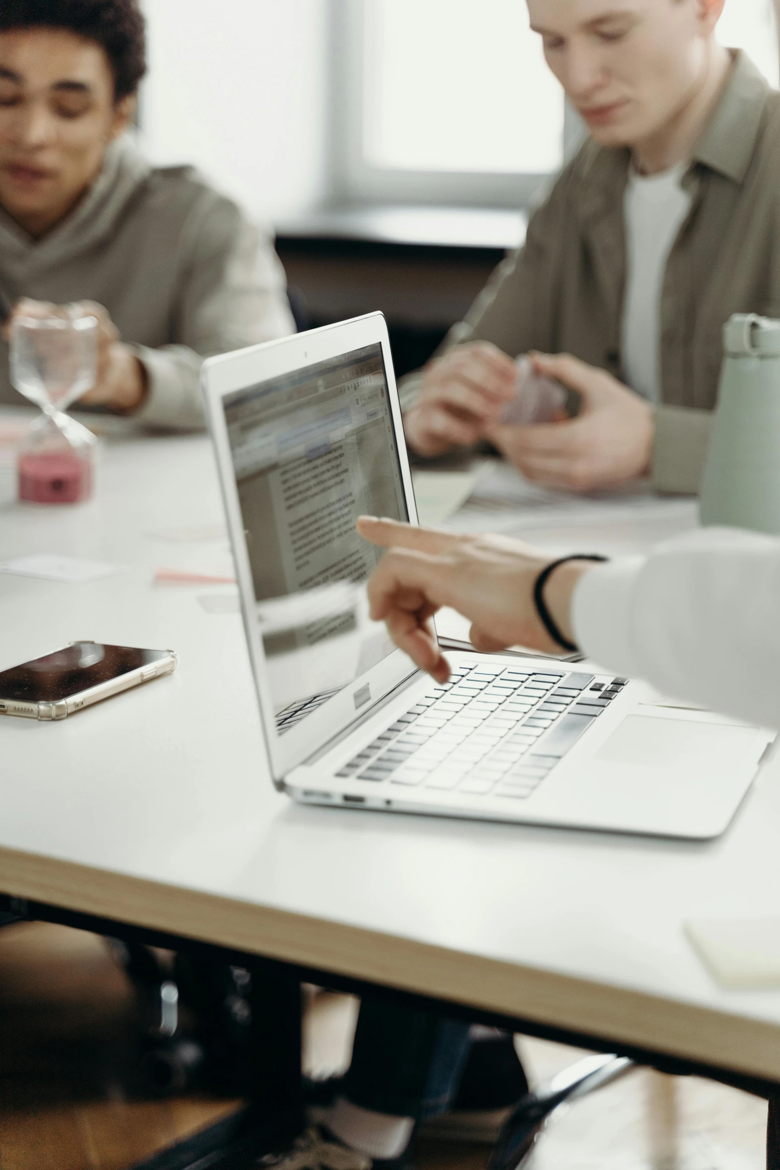 a group of people sitting around a table with a laptop, zoomed in, thumbnail, high quality image