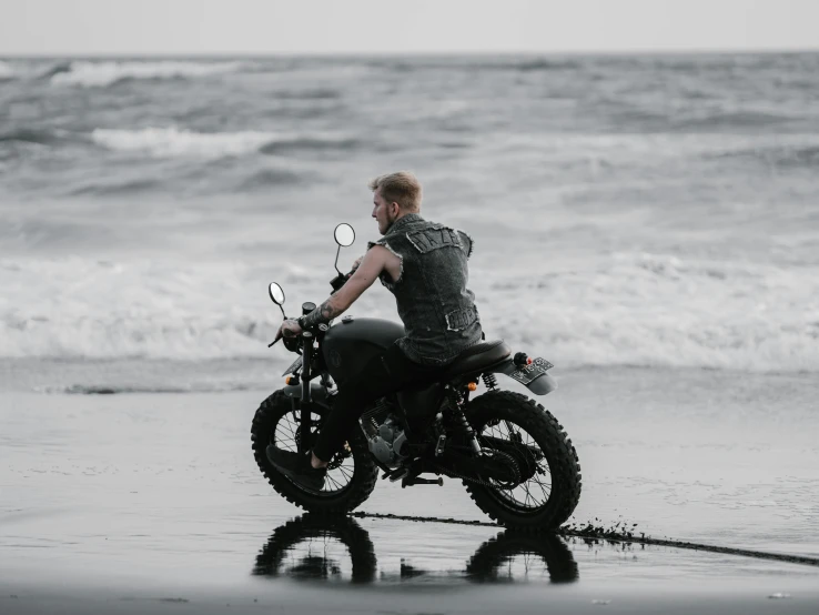 a man riding a motorcycle on top of a wet beach, pexels contest winner, braided beard redhead dreadlocks, full body image, gray, classic gem