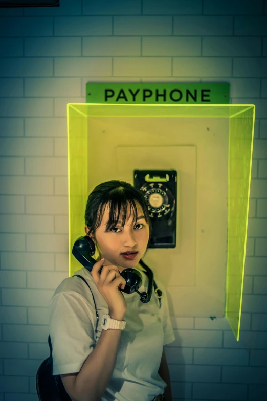 a woman standing in front of a pay phone, by Miyamoto, pexels contest winner, ((yellow magic orchestra)), green neon, softplay, headset