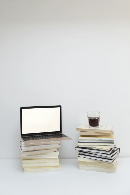 a laptop computer sitting on top of a stack of books, drink, julia sarda, white space in middle, null