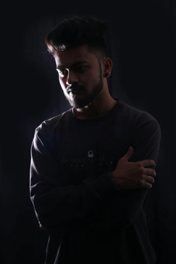 a man standing in the dark with his arms crossed, a character portrait, pexels contest winner, hurufiyya, studio!! portrait lighting, discord profile picture, ayan nag, casual pose