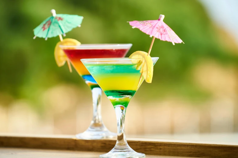 a couple of drinks sitting on top of a table, inspired by Ndoc Martini, unsplash, colorful umbrella, jamaican colors, profile image, multicoloured