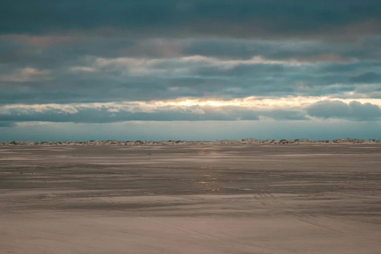 a person riding a horse on a beach under a cloudy sky, by Eglon van der Neer, unsplash contest winner, australian tonalism, desolate arctic landscape, wide long view, evening sunlight, blue sand