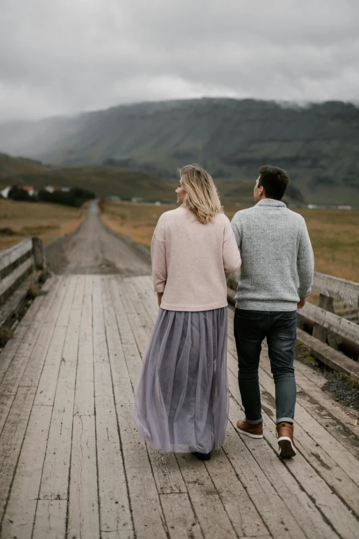 a man and a woman walking on a wooden bridge, by Hallsteinn Sigurðsson, trending on unsplash, romanticism, grey, fully dressed, looking from behind, road