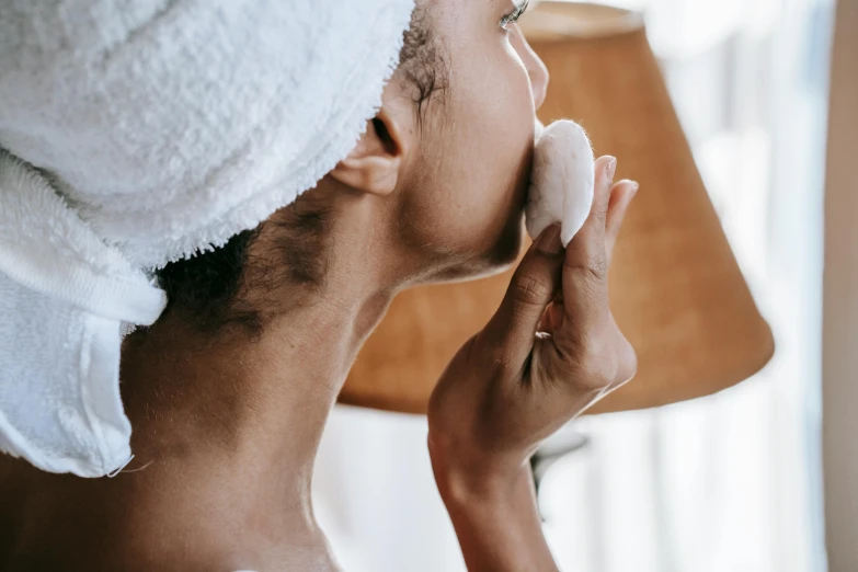 a woman with a towel on her head brushing her teeth, a photo, by Emma Andijewska, trending on pexels, skin tones, sideview, manuka, pearl earring
