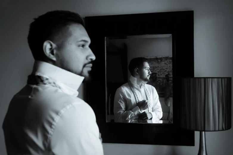 a man that is standing in front of a mirror, in the evening