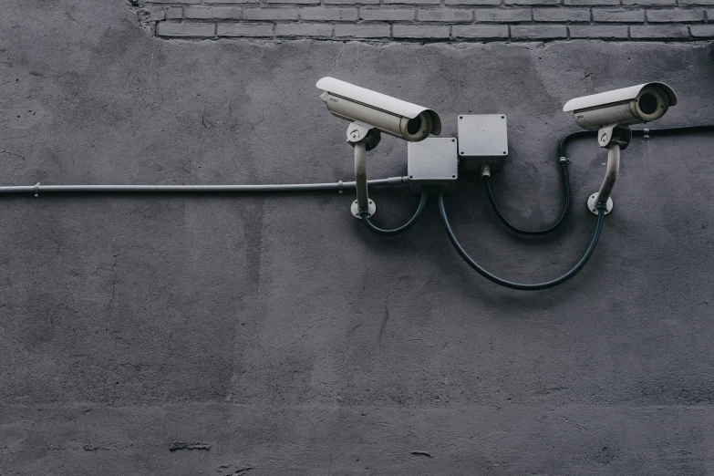 two surveillance cameras mounted on the side of a building, unsplash, les automatistes, broken down grey wall, background image, pipes, secuirty cam footage