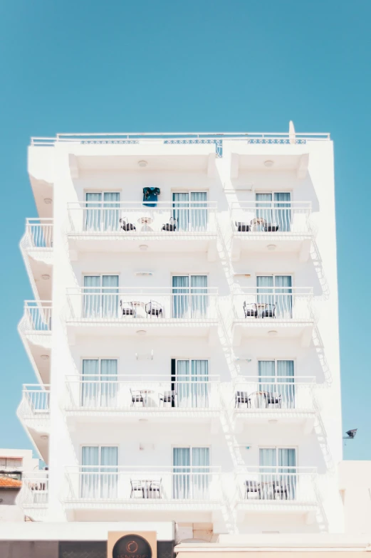 a tall white building with balconies and balconies on the balconies, a photo, unsplash contest winner, hotel room, beach aesthetic, bright render, white and pale blue