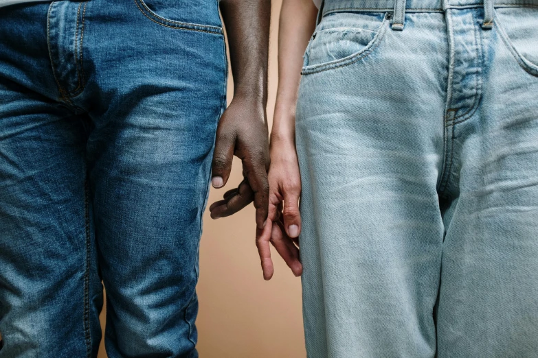 a close up of two people holding hands, by Carey Morris, trending on pexels, renaissance, ( ( ( wearing jeans ) ) ), diverse colors, plain background, brown