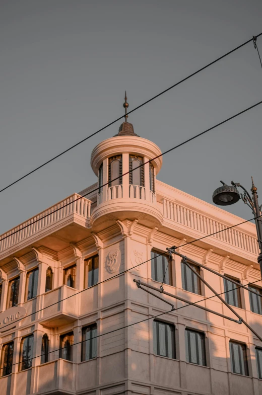 a tall white building sitting on the side of a street, by Michalis Oikonomou, unsplash contest winner, berlin secession, golden hour closeup photo, wires and lights, persian style architecture, turrets