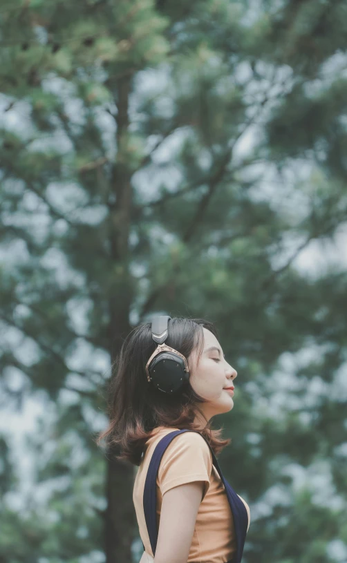 a woman with headphones standing in front of a tree, trending on pexels, aestheticism, portrait of a japanese girl, low quality photo, profile image, thoughtful )