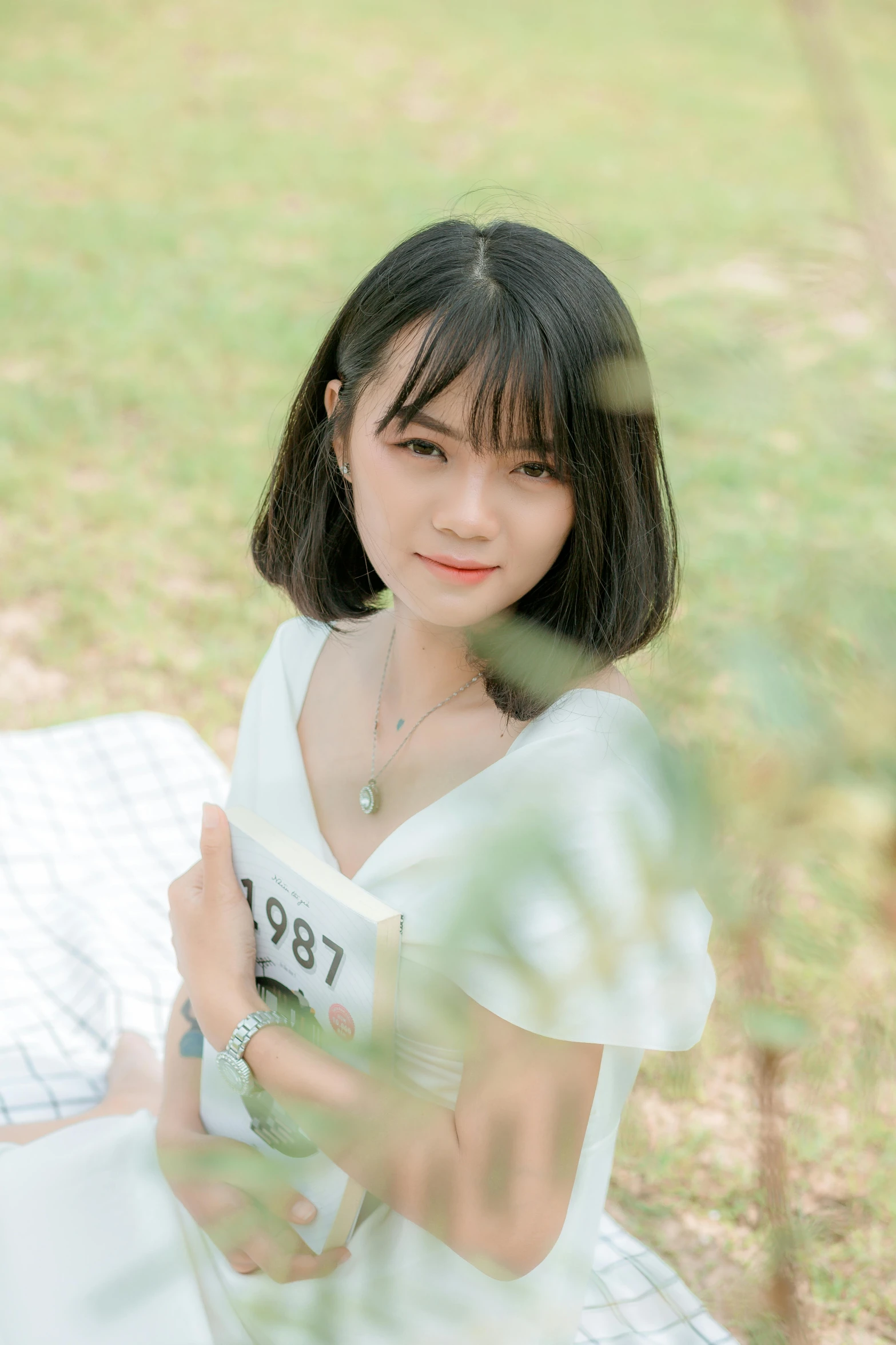 a woman sitting on a blanket in the grass, a picture, inspired by Ma Yuanyu, pexels contest winner, realism, with a bob cut, 🤤 girl portrait, good young girl, headshot profile picture
