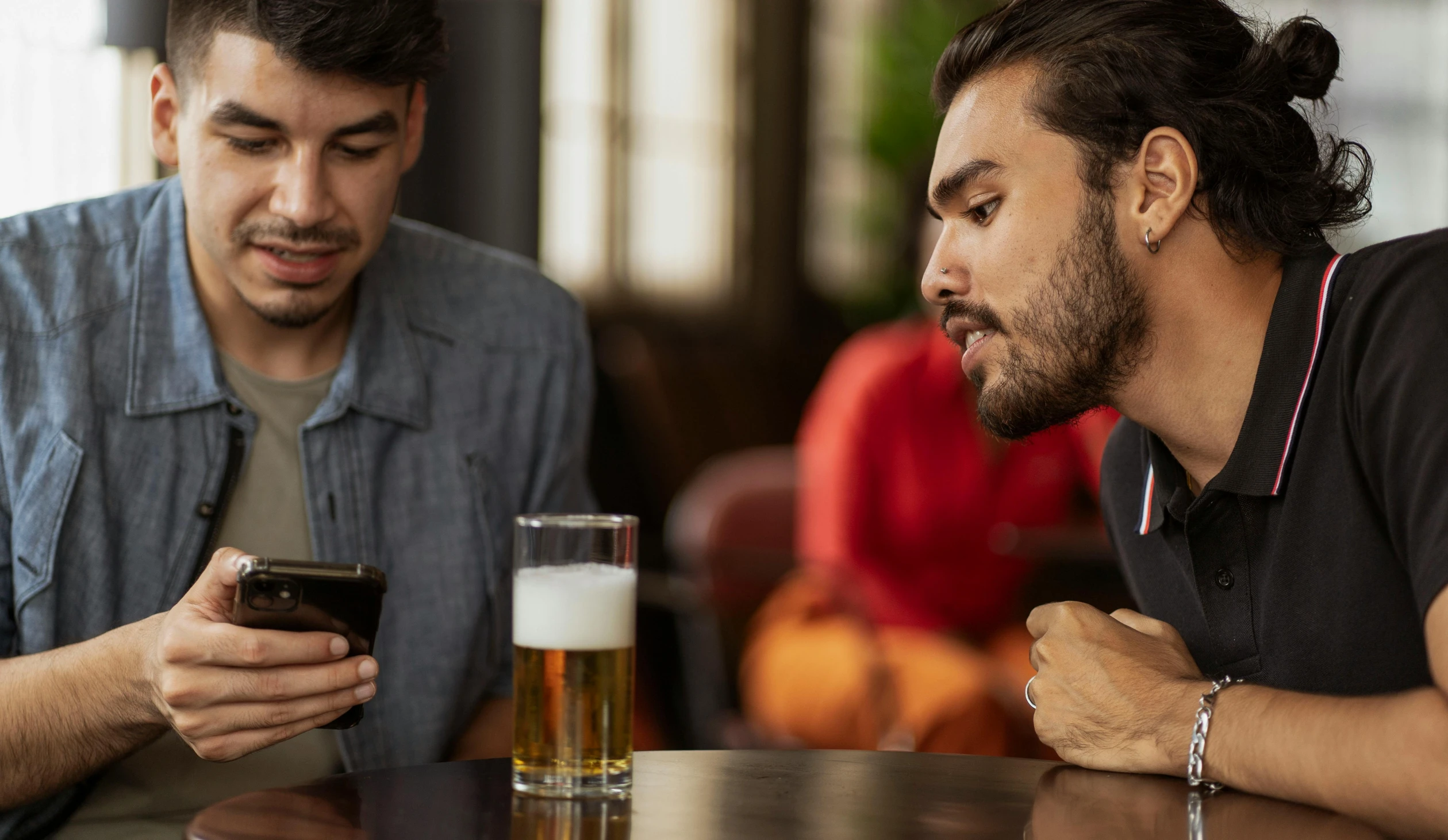 two men sitting at a table looking at a cell phone, trending on pexels, renaissance, a pint of beer sitting on a bar, aussie baristas, tense, two young men