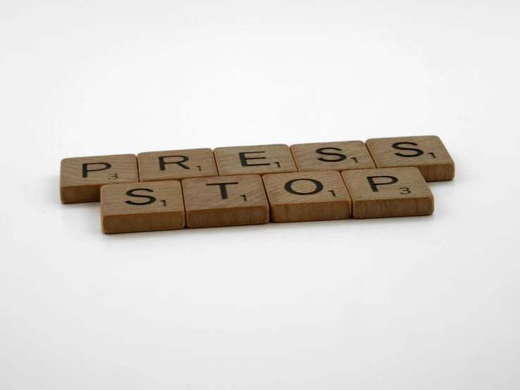 a wooden block with the word press stop written on it, by Matthias Stom, private press, product shot, grey, blocks, compressed