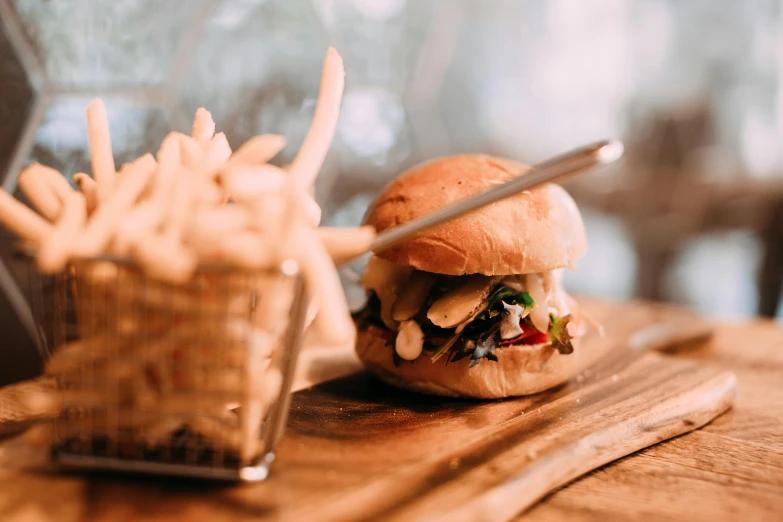 a wooden cutting board topped with a sandwich and french fries, unsplash, bao phan, profile image, blurred photo, background image