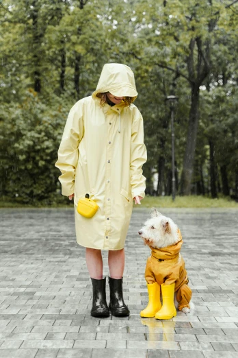 a woman standing next to a dog in a raincoat, inspired by Elke Vogelsang, shutterstock, square, colors: yellow, lifestyle, duck shoes
