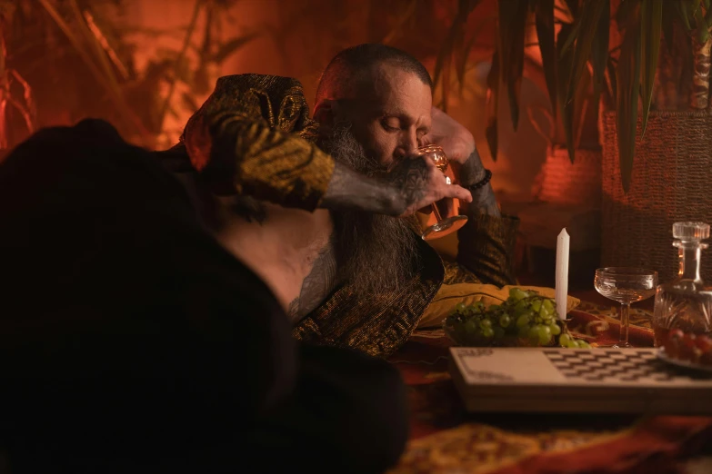 a man sitting at a table with a glass of wine, an album cover, inspired by Pieter Aertsen, pexels contest winner, celtic druid, alex grey and dan hillier, smoking a bowl of hash together, shot from cinematic