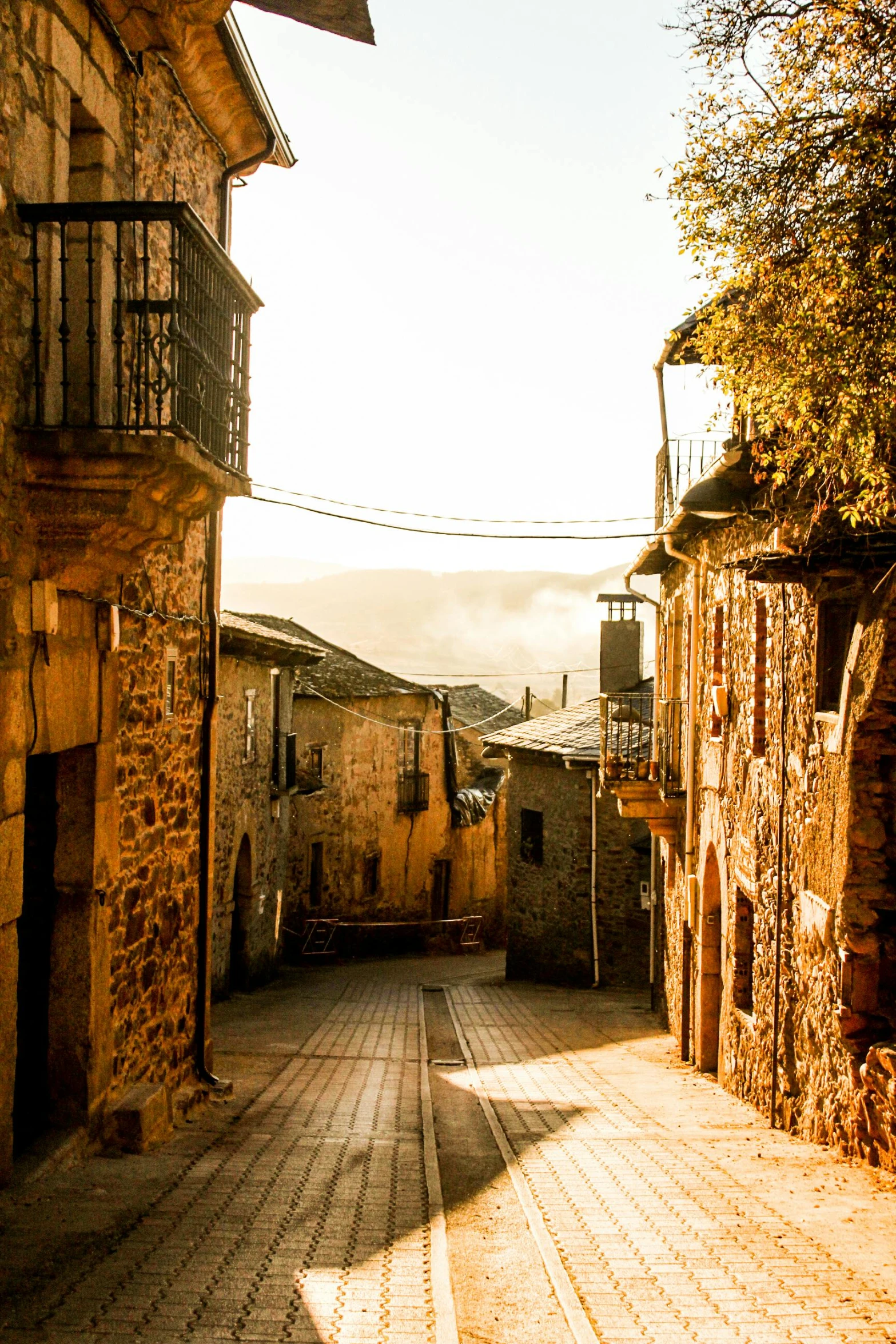 a narrow cobblestone street in an old town, an album cover, inspired by Modest Urgell, pexels contest winner, 2 5 6 x 2 5 6 pixels, view of villages, golden morning light, in spain