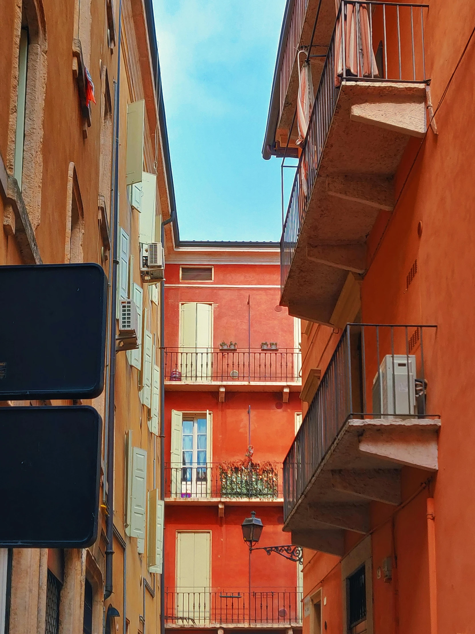 a street sign hanging from the side of a building, a photo, pexels contest winner, neo-fauvism, red building, mediterranean city, colors orange, french village exterior