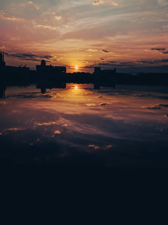 the sun is setting over a body of water, pexels contest winner, city reflections, dark mood, high quality image”, album cover