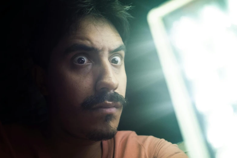 a man sitting in front of a computer monitor, a portrait, pexels contest winner, mexican mustache, lightbeam eyes, frightened look, raden saleh