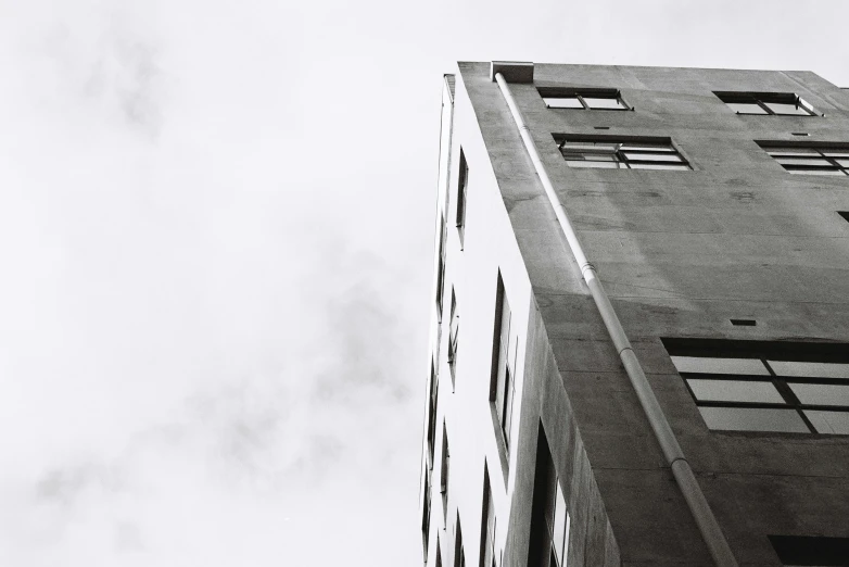 a black and white photo of a tall building, inspired by André Kertész, unsplash, gray concrete, fine art print, skies, view from side