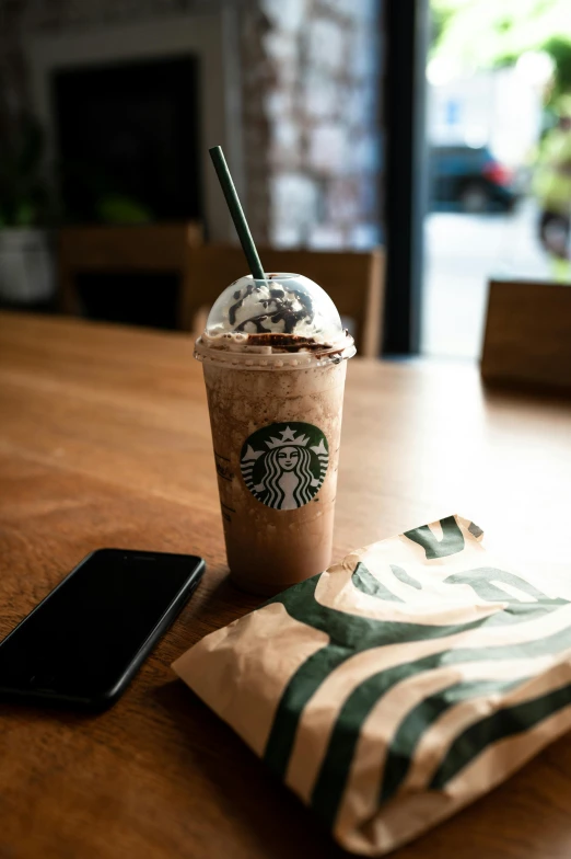 a starbucks drink sitting on top of a wooden table, inspired by Elsa Bleda, chocolate. rugged, full device, no color, snacks
