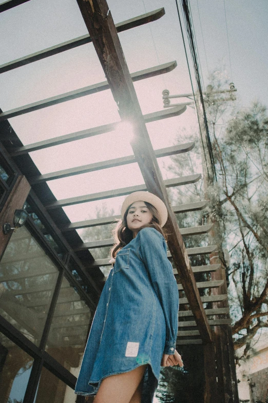 a woman standing in front of a glass building, by Tan Ting-pho, unsplash, wearing a cowboy hat, wearing double denim, in a tree house, ulzzang