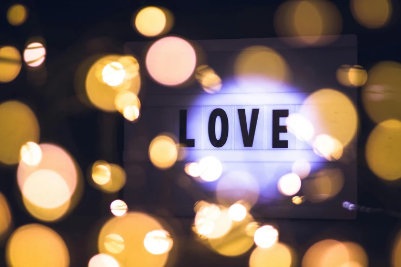 a sign that says love with bokeh lights in the background, trending on pexels, light and space, avatar image