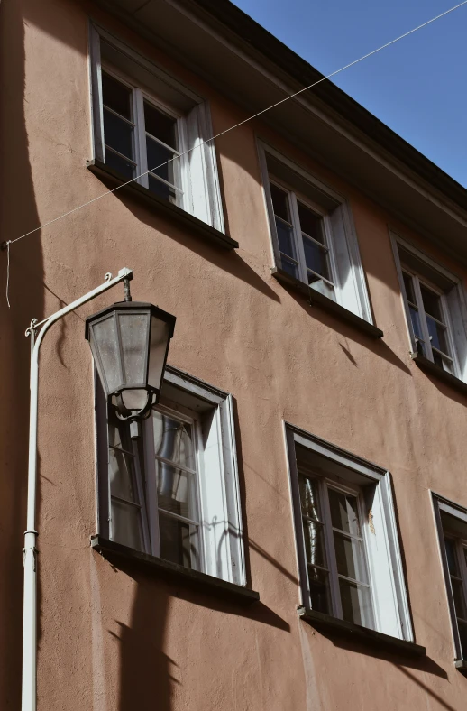 a building with a street light in front of it, inspired by Mihály Munkácsy, light - brown wall, old town, window, wires hanging