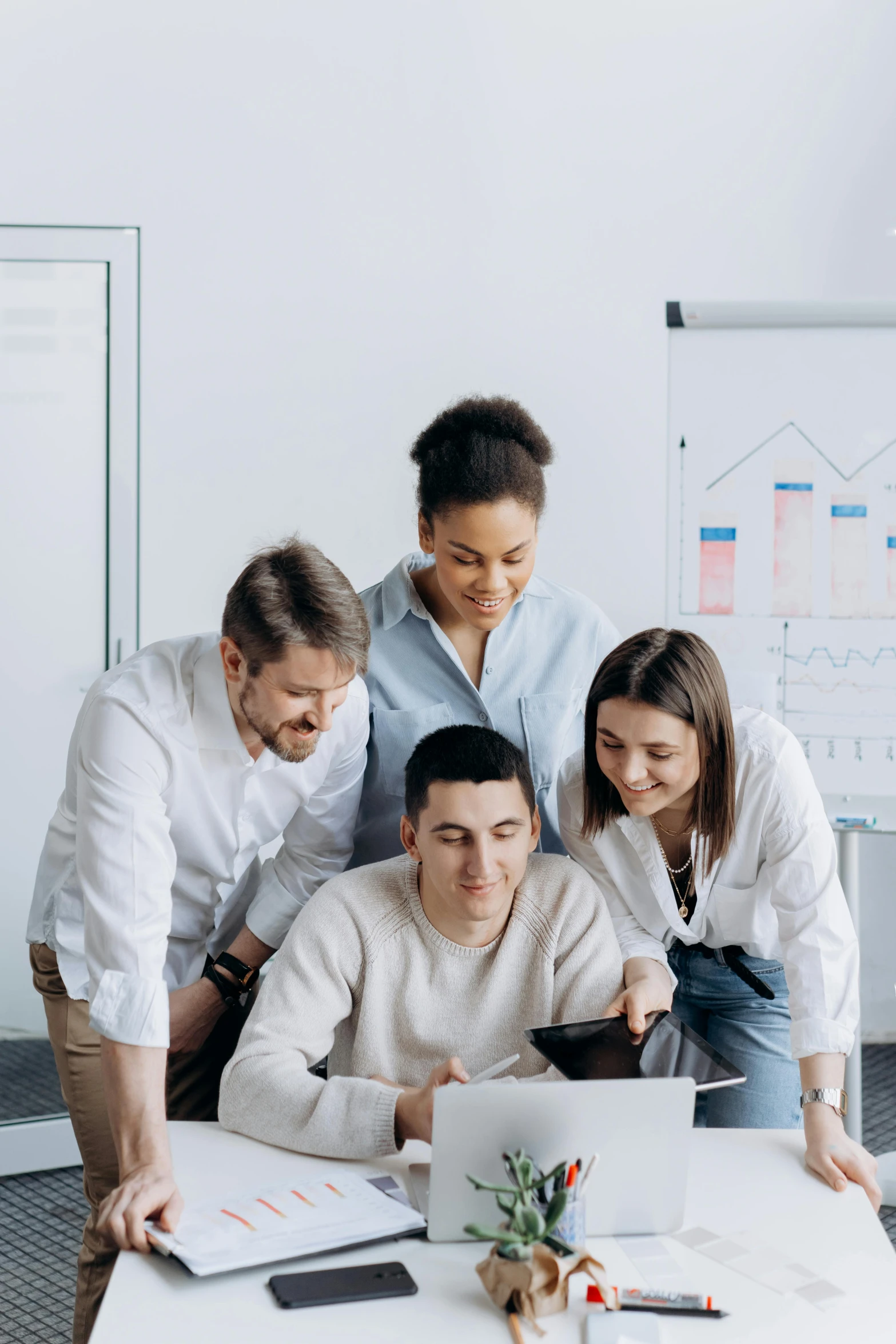 a group of people standing around a table with a laptop, on top of it