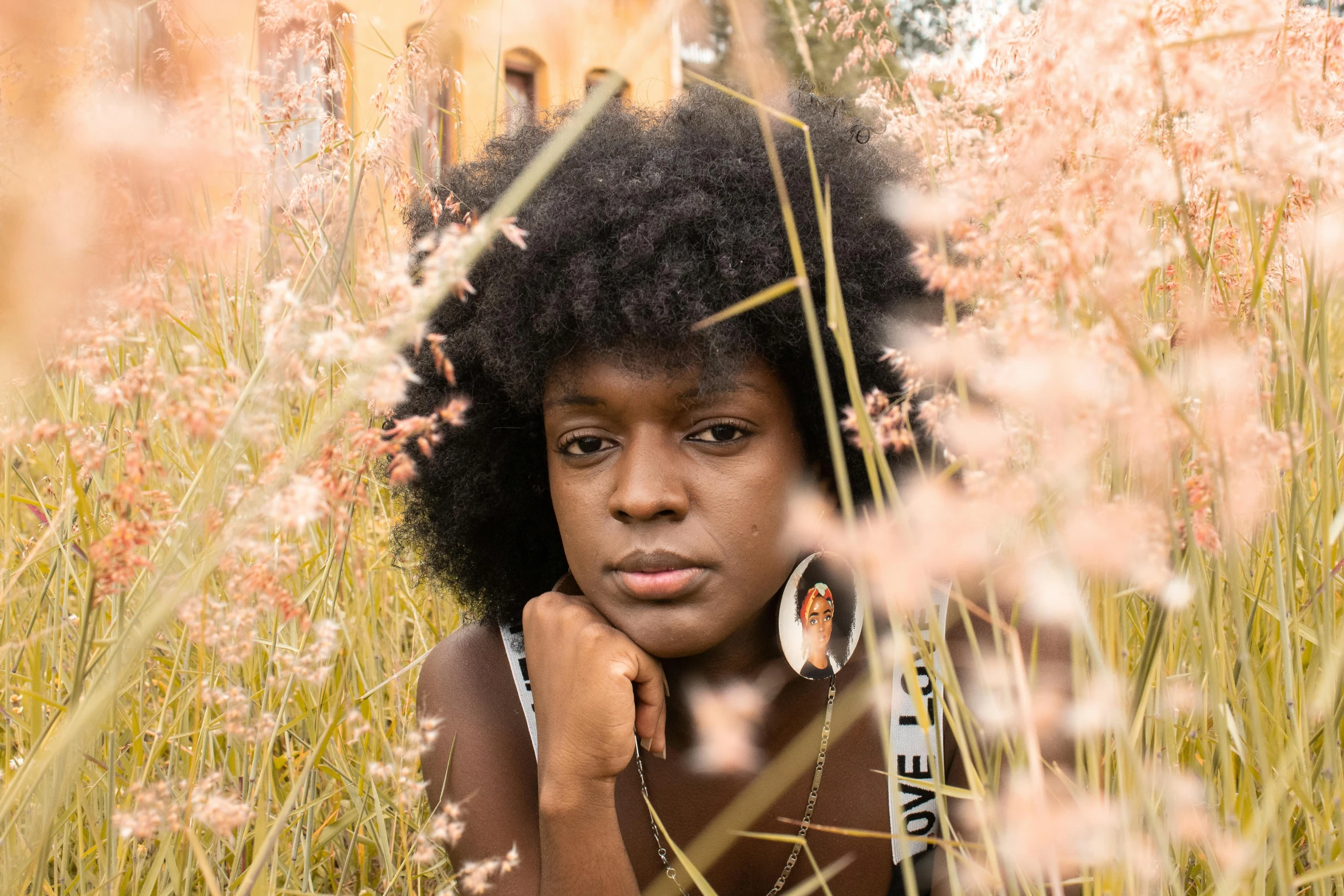 a woman sitting in a field of tall grass, by Lily Delissa Joseph, pexels contest winner, renaissance, ( brown skin ), headshot, afro, medium format