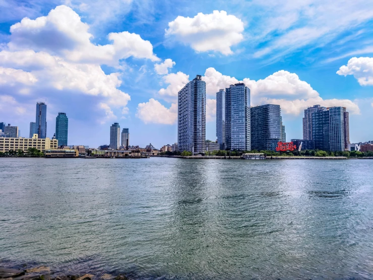 a large body of water surrounded by tall buildings, pexels contest winner, hyperrealism, background image, partly cloudy day, shoreline, philippines