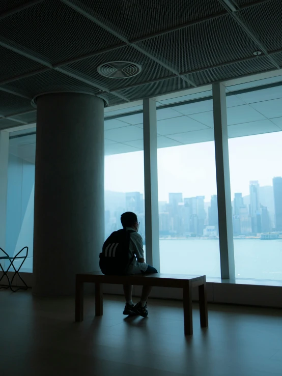 a person sitting on a bench looking out a window, inspired by Fei Danxu, visual art, 4k museum photograph, hong kong, instagram picture, distant full body view