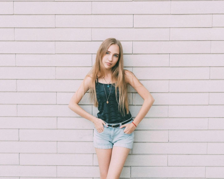a girl leaning against a wall with her hands on her hips, pexels contest winner, wearing a camisole and shorts, teen girl, carson ellis, jovana rikalo